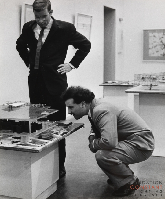 Constant Nieuwenhuys-Schulze Fielitz, German architect, and Swiss painter André Thomkins in front of model Red Sector, 1961
